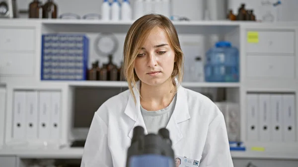 In the heart of science, young attractive blonde woman scientist intently working with microscope at laboratory, brewing discoveries through analysis