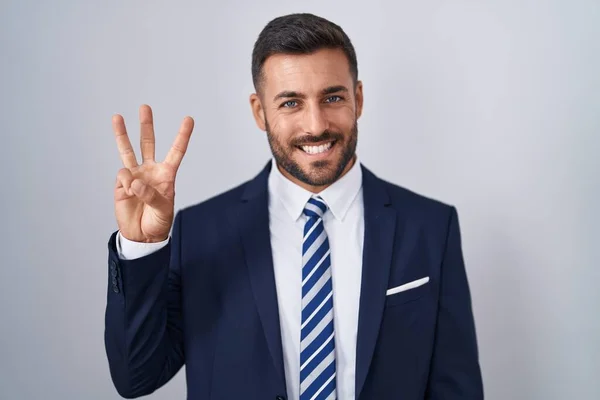 ハンサムなヒスパニックの男性は 自信と幸せに微笑んでいる間 スーツとネクタイを示し 指番号3を指で指摘しています — ストック写真