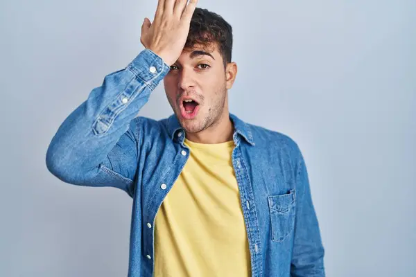 Ung Latinamerikansk Man Står Över Blå Bakgrund Överraskad Med Handen — Stockfoto