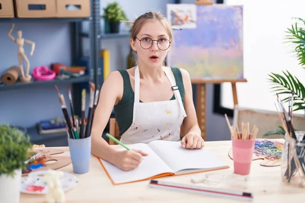 身穿学生服的年轻高加索女人坐在桌旁 用艺术调色板 — 图库照片