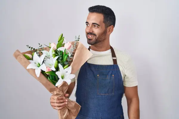 Hispanic man with beard working as florist looking away to side with smile on face, natural expression. laughing confident.