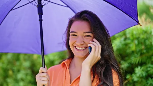 Young Beautiful Hispanic Woman Holding Umbrella Talking Smartphone Park — Stock Photo, Image