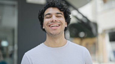 Young latin man smiling confident standing at street