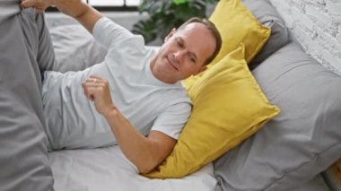 Yakışıklı, orta yaşlı İspanyol adam rahat yatak odasında dinleniyor, yorucu bir günün ardından uykuya dalmaya hazırlanıyor.