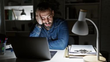 Yorgun genç bir İspanyol, çok çalışan bir iş adamı, ofis masasında gece lambası yanıyor.