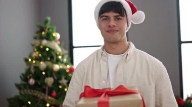 Genç İspanyol adam gülümsüyor kendine güveni tam evde Noel hediyesini kucaklıyor