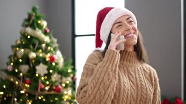 Genç, güzel, İspanyol bir kadın akıllı telefondan Noel 'i evde kutluyor.