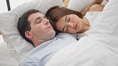 Yatakta uzanıp kafa üstü öpüşen güzel bir çift yatak odasında uyuyor.