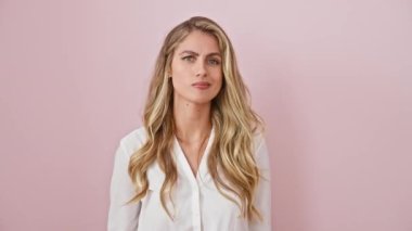 Şaşkın genç sarışın bir kadın gömlek giyiyor, kollarını çaresiz bir omuz silkip duruyor, pembe izole bir arka planda habersiz ve kafası karışık. Hiçbir fikrim yok..