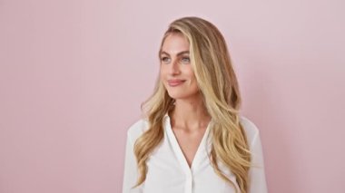 Gömlek giyen genç sarışın kadın çok mutlu duruyor ve gülümsüyor. Çok uzaklara bakıyor. arama konsepti. izole edilmiş pembe arkaplan