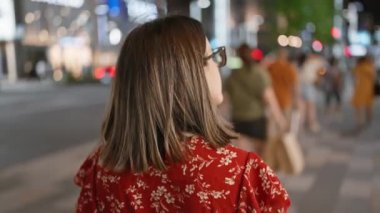 Gözlüklü, güzel İspanyol bir kadın gece vakti Tokyo sokaklarına bakıyor. Sıradan bir karizma yayıyor.