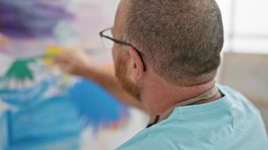 Yakışıklı, orta yaşlı, beyaz bir adam. Kapalı mekan sanat stüdyosunda tutkuyla bir portre çizerken son derece konsantre olan bir sanatçı.