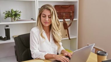 Güzel, kendine güvenen ve gülümseyen genç sarışın bir iş kadını bilgisayarındaki ve akıllı telefonundaki konuşmaları ustaca yönetiyor. Başarıyı zarif gösteriyor..