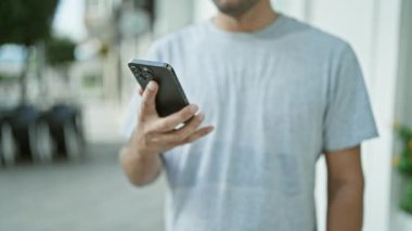 Neşeli genç adam telefonda konuşuyor, sokak yürüyüşünde gülümsemesini gösteriyor.