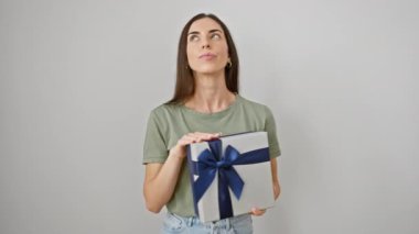 Düşünceli genç İspanyol kadın elinde bir doğum günü hediyesi paketiyle ciddi ciddi bir soru düşünüyor. Kafası karışık ama düşünceli, elini çenesine koyup izole edilmiş beyaz bir arka plana koyuyor..