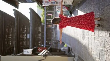Kendine güvenen, güzel İspanyol bir kadın kollarını açmış, gülümsüyor ve Kyoto 'nun geleneksel lejyon sokaklarına bakıyor.