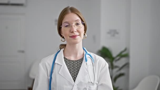 Joven Rubia Doctora Sonriendo Confiada Pie Con Los Brazos Cruzados — Vídeo de stock