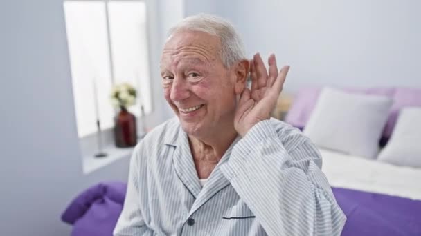 Radosny Starszy Pan Siedzący Łóżku Piżamie Nadętym Uchem Chcący Usłyszeć — Wideo stockowe