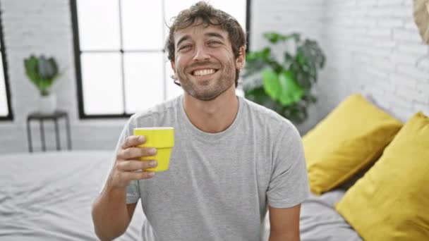 Χαρούμενος Νεαρός Καφέ Στο Χέρι Κάθεται Στο Κρεβάτι Του Πρωί — Αρχείο Βίντεο