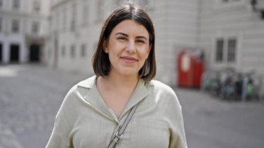 Genç ve güzel İspanyol kadın gülümseyerek Viyana sokaklarına bakıyor.