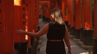 Büyüleyici, gözlüklü, büyüleyici bir İspanyol kadını Fushimi 'deki canlı turuncu tori kapılarından geçerek geleneksel Japon kültürünün özünü somutlaştırıyor..