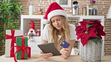 Genç sarışın kadın dokunmatik ped ve kredi kartıyla alışveriş yapıyor. Noel 'i yemek odasında kutluyor.