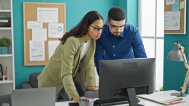 İşteki dinamik ikili, iki profesyonel işçi, erkek ve kadın, ofislerinin içindeki masalarında başarıyı büyülüyorlar, bilgisayarla teknolojiyi kullanıyorlar.