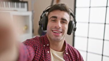 Kendine güvenen genç İspanyol müzisyen, sanatçı içeride gösteri yapıyor, melodi dinliyor, video stüdyosunda tutkuyla konuşuyor, kulaklık takıyor, şarkı söylerken gülümsüyor..