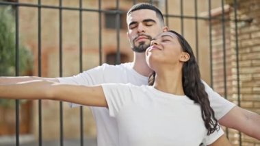 Güzel bir çift bir arada duruyor, kolları açık, güvenli bir şekilde şehirde nefes alıyorlar, güneşli bir sokakta aşklarının tadını çıkarıyorlar..