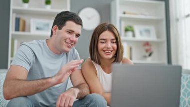 Kanepede birlikte oturan güzel bir çift evde video görüşmesi yapıyorlar.