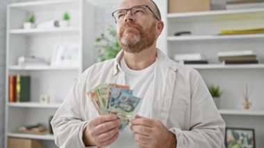 Yakışıklı, sakallı, beyaz bir adam, bir iş ofisinde çalışıyor, Avustralya dolarlarını sayarken ciddi ciddi belirsiz geleceği düşünüyor, yatırım stratejisinden şüphe ediyor..
