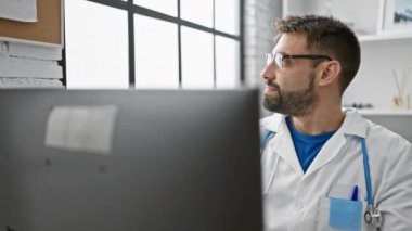 Genç İspanyol doktor bilgisayar kullanıyor. Kliniğe bakıyor.