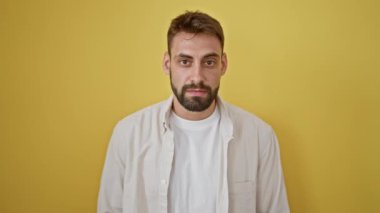 Sersemlemiş genç İspanyol bir adam saate bakıyor, sarı arka planda izole edilmiş sürpriz bir geri sayım zamanlayıcısının portresi.!