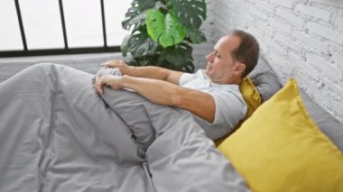 Yakışıklı orta yaşlı adam kollarını uzatıyor, sabah ışığını kucaklıyor rahat yatak odasına dökülüyor, rahat bir şekilde uyanıyor, yeni bir güne yeni bir canlılık ile başlıyor evin konforu arasında.