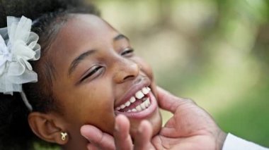 Afrika kökenli Amerikalı baba ve kız parkta yüz yüze duruyorlar.