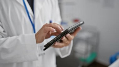 Yakışıklı orta yaşlı bilim adamı, yoğun tıbbi araştırmaların ortasında klinik laboratuarında dokunmatik ped kullanarak teknolojinin içine dalıyor.