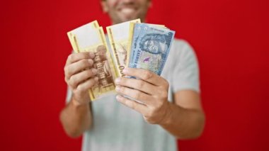 Güler yüzlü genç adam mutlu bir şekilde onun Hungary Forint banknotlar, izole, canlı kırmızı zemin karşı duran güvenle duruyor