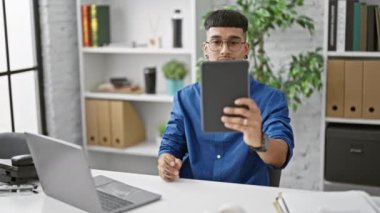 Ofisteki dokunmatik pedi ile selfie çekerken kıkırdayan yakışıklı Latin bir adam.