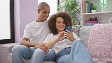 Kanepede oturan güzel çift evde akıllı telefon beşliği kullanıyor.