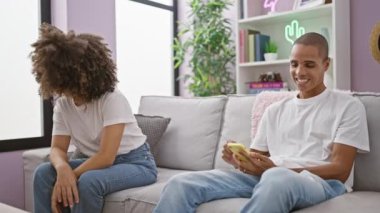 Evdeki kanepede oturan mutsuz, güzel bir çift, erkek arkadaşı akıllı telefona dalmış, mutlu aşkını görmezden geliyor.