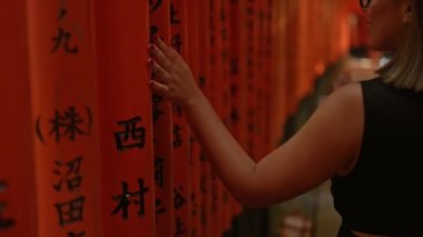 Büyüleyici, gözlüklü, büyüleyici bir İspanyol kadını Fushimi 'deki canlı turuncu tori kapılarından geçerek geleneksel Japon kültürünün özünü somutlaştırıyor..