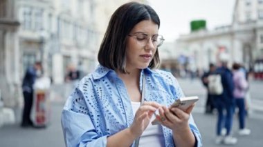 Akıllı telefon kullanan genç, güzel İspanyol kadın Viyana sokaklarında birini bekliyor.