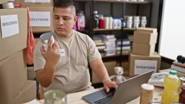 Gönüllü bir genç Latin gönüllü sosyal yardım merkezinin kalbindeki laptopunda konserve yiyecekleri kontrol ediyor..