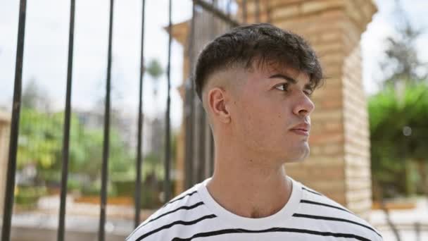 Прохолодний Спокійний Молодий Іспаномовний Чоловік Зображує Серйозне Вираження Стоячи Вулиці — стокове відео