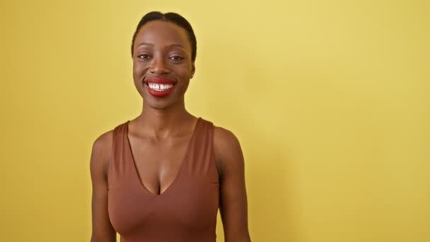 快乐的非洲裔美国女人打出了一个极好的认可信号 竖起大拇指 散发着积极向上的光芒 她孤零零地站在黄色的背景上 笑脸惊呼成功 — 图库视频影像