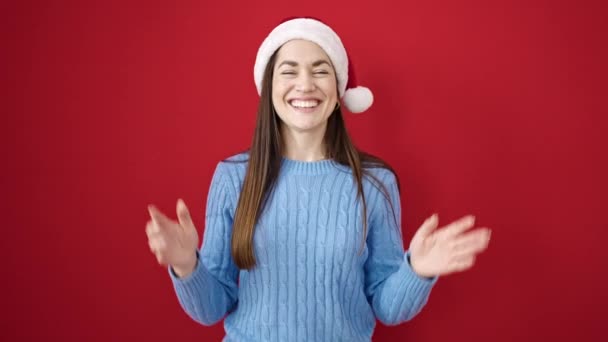 年轻的高加索女人头戴圣诞礼帽 在孤立的红色背景上拍手 — 图库视频影像