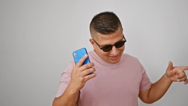 孤立した白い背景上のスマートフォンで音楽を聴くダンスの若いラテン人の男 — ストック動画