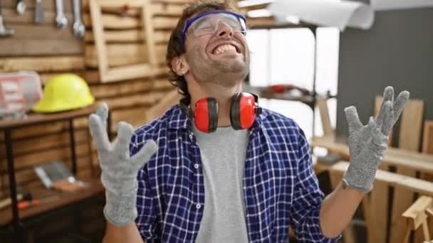 一个激动的年轻人 一个成功的木匠 高兴得发疯了 举起双臂 笑着庆祝他在木工方面的伟大胜利 — 图库视频影像