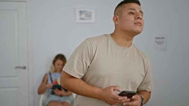 Besorgter Junger Lateinischer Mann Wartezimmer Vertieft Ernste Sms Probleme Auf — Stockvideo