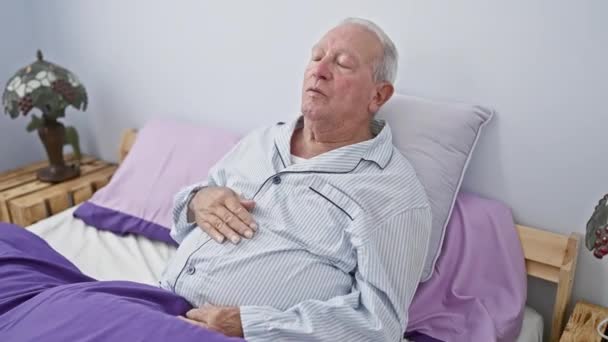 穿着睡衣的老人痛苦地坐在床上抓着肚子胃痛 便秘或家中恶心的疾病表现 — 图库视频影像